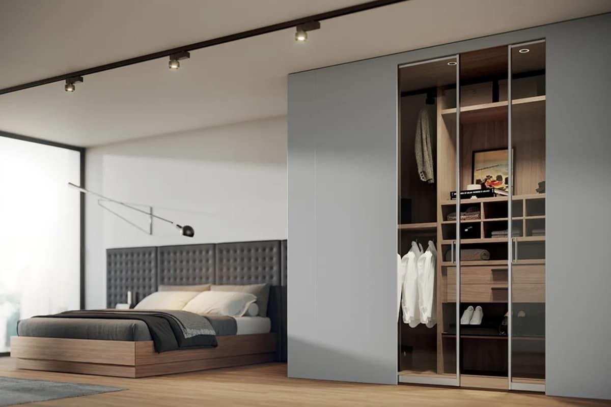 Camera matrimoniale con cabina armadio con ante in vetro e letto contenitore con boiserie imbottita